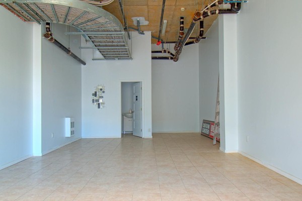 Large, open commercial interior with exposed pipes, tiled floors, and a small washroom. - 1180 Ch. D'aylmer, #ss04, Gatineau