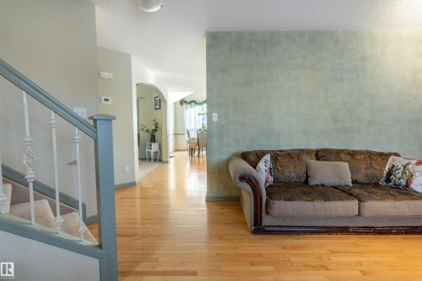 View from the living room towards the staircase, hallway, and dining area with wooden floors. - 11813 12 Av Nw, Edmonton