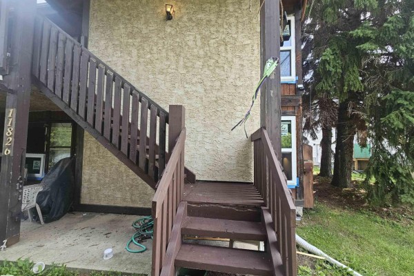 Close-up of wooden stairs and railing leading to an upper unit entrance. - 11822 39 St Nw, Edmonton