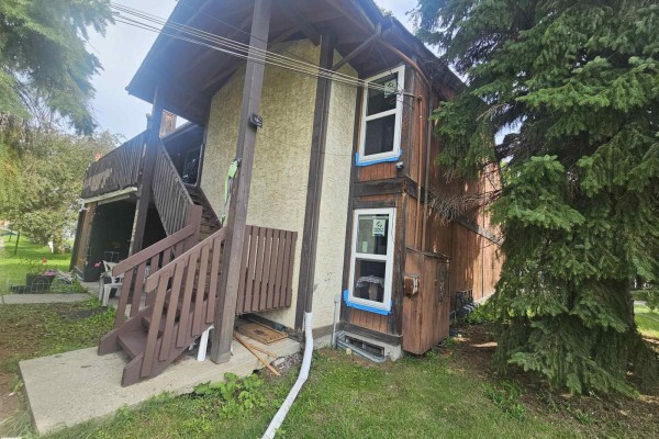 Side view of the fourplex exterior showing wood siding, trees, and windows. - 11822 39 St Nw, Edmonton