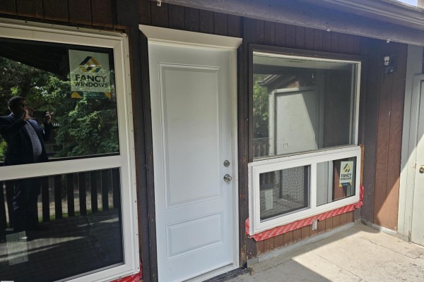 Entrance door and windows on the fourplex exterior with wood siding. - 11822 39 St Nw, Edmonton