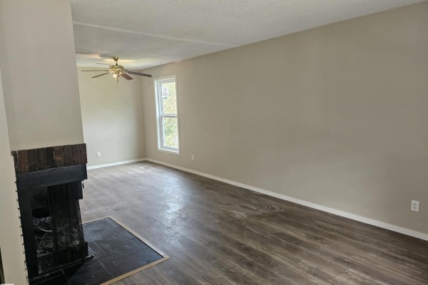 Living room with beige walls, dark laminate flooring, and a brick fireplace. - 11822 39 St Nw, Edmonton