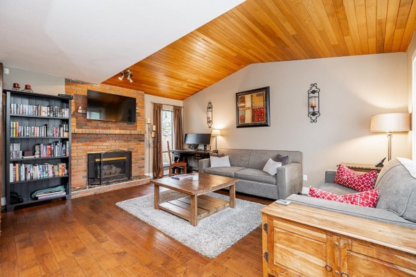 Living room with a grey sectional sofa, wooden coffee table, and a view of the stairs and entryway. - 11826 Alderwood Crescent, Delta