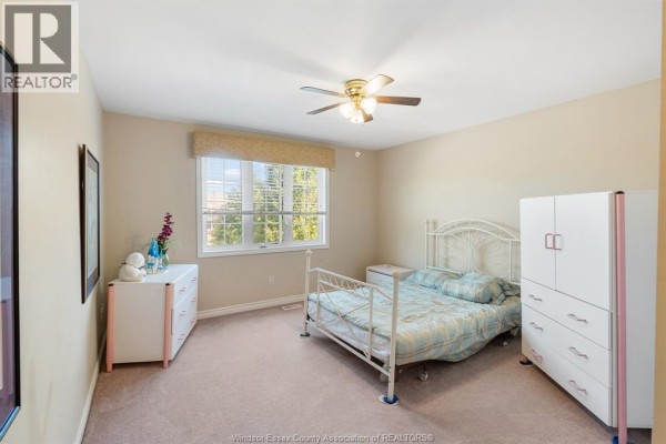 Bedroom with a four-poster bed, hardwood floors, a closet, and a ceiling fan. - 11827 Boulder Crescent, Windsor