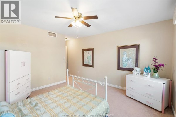 Finished basement room with tile floors, a wooden ceiling, and a large display cabinet. - 11827 Boulder Crescent, Windsor