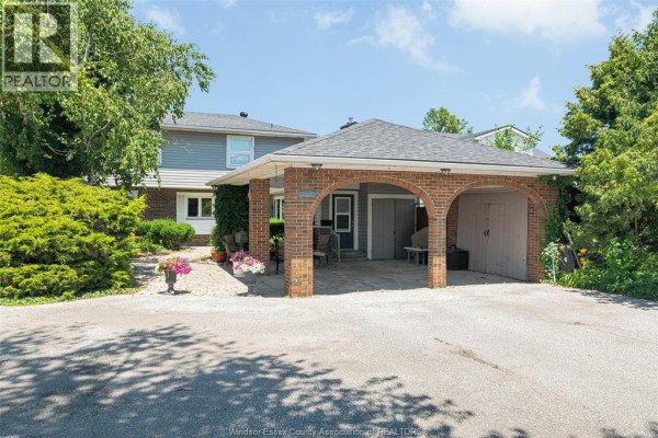 View of a house with a brick carport, garage door, and front entrance. - 11830 Riverside Drive East, Windsor