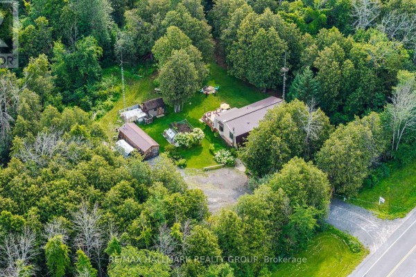 Aerial view of a house and outbuildings surrounded by a dense forest. - 1184 Derry Side Road, Beckwith