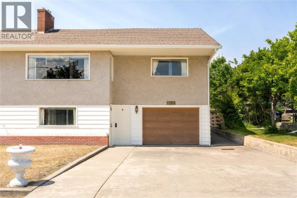 Front exterior of 1188 Hartwick Street showing a beige stucco facade and brown garage door. - 1188&1190 Hartwick Street, Kelowna