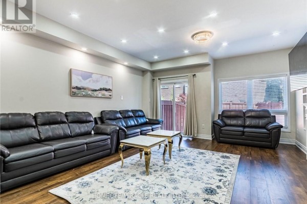 Living room with dark leather sofas, two gold-trimmed coffee tables, and a patterned rug. - 119 - 110 Highland Road, Kitchener