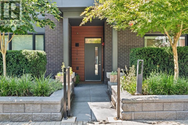 Entrance pathway to townhouse unit 119 with dark grey door and wood paneling. - 119 2035 Glenaire Drive, North Vancouver