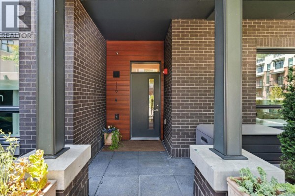 Close-up of townhouse entrance with grey door, brick exterior, and potted plants. - 119 2035 Glenaire Drive, North Vancouver