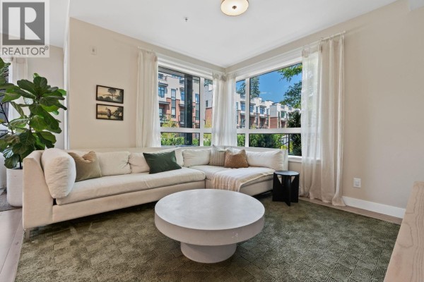 Living room with large sectional sofa, round coffee table, and corner windows with view. - 119 2035 Glenaire Drive, North Vancouver