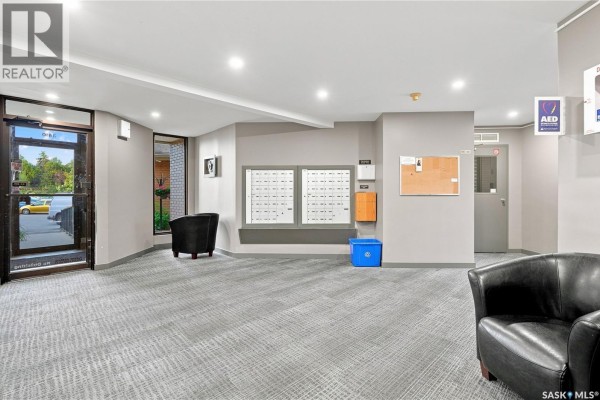 Apartment building lobby with mailboxes, bulletin board, and seating area. - 119 3410 Park Street, Regina