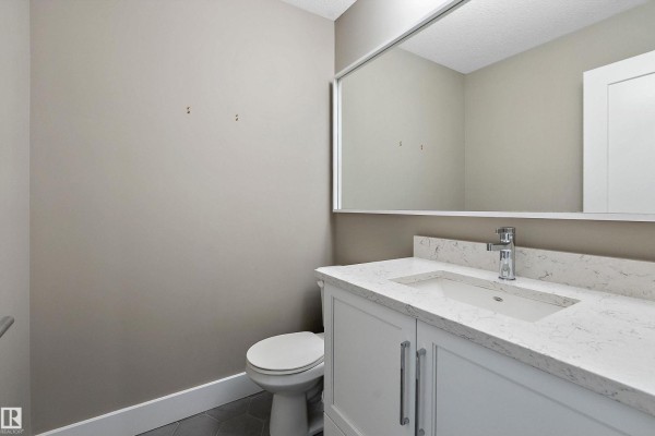 A powder room with a beige vanity, white quartz countertop, and stainless steel faucet. - #119 524 Griesbach Pr Nw Nw, Edmonton
