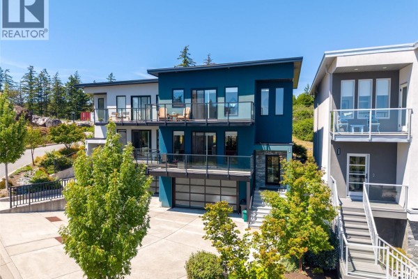 Aerial view of modern townhouses with solar panels on a hillside overlooking the ocean. - 119 539 Delora Dr, Colwood