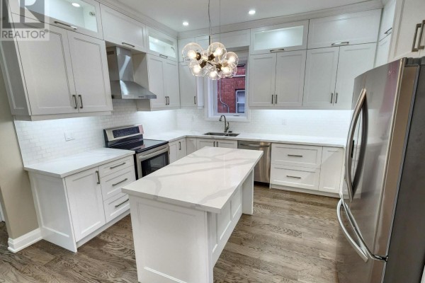 Modern white kitchen with quartz countertops, stainless steel appliances, and a central island. - 119 Colborne Street E, Oshawa