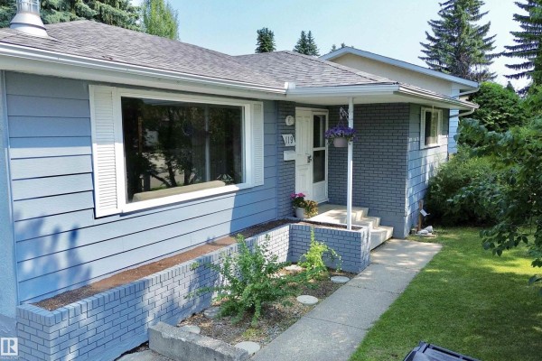 Close-up of the light blue house exterior with a prominent window and brick accents. - 119 Garland Cr, Sherwood Park
