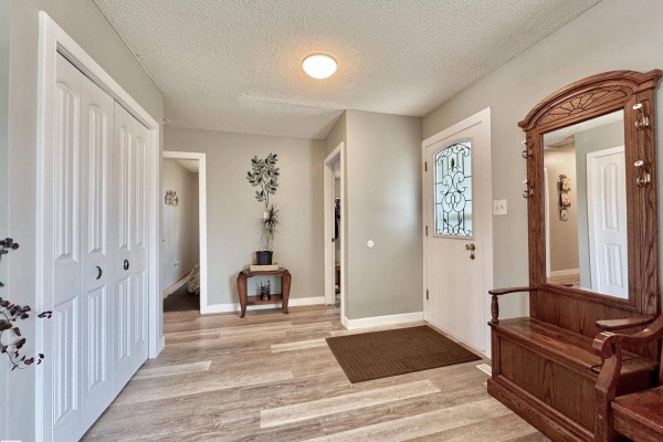 Interior front entryway with light grey walls, double white closet doors, and a wooden bench. - 119 Garland Cr, Sherwood Park