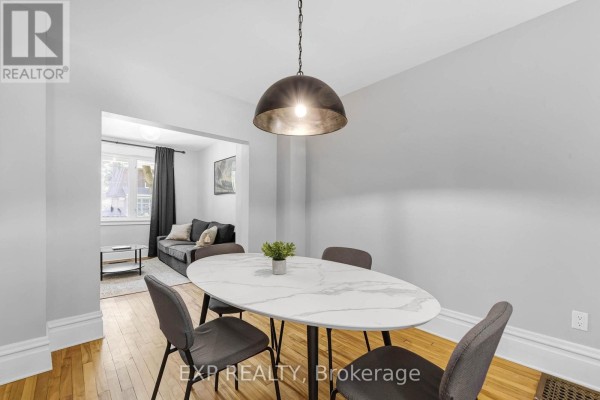 Dining area with an oval marble-topped table, grey chairs, and a modern pendant light. - 119 Hopewell Avenue, Ottawa