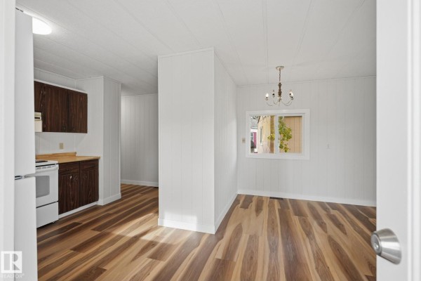 View of the kitchen and adjacent dining area with white paneled walls and wood-look flooring. - 119 Parkland Acres, Lacombe
