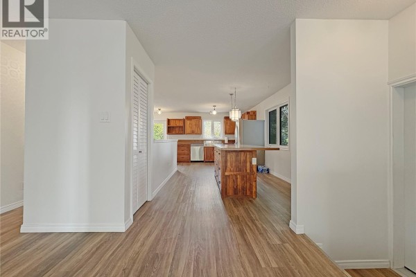 Living room with grey walls, wood-look laminate flooring, and a large window with a tree view. - 119 Prairie Street, Dalmeny