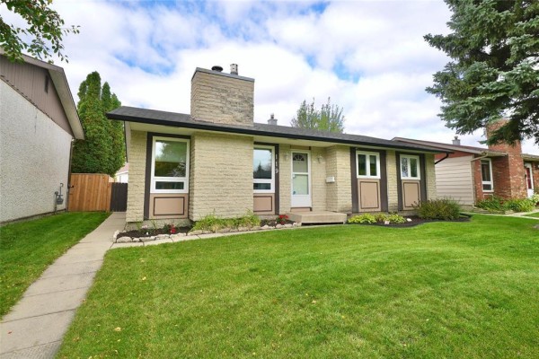 Side view of the front exterior of the house, showing a paved walkway and lawn. - 119 Sanderson Avenue, Winnipeg