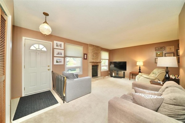 Living room with carpet, neutral walls, sofa, armchair, and brick fireplace. - 119 Sanderson Avenue, Winnipeg