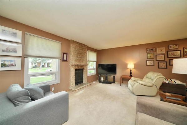 Living room showcasing a stone fireplace, television, seating area, and large windows. - 119 Sanderson Avenue, Winnipeg