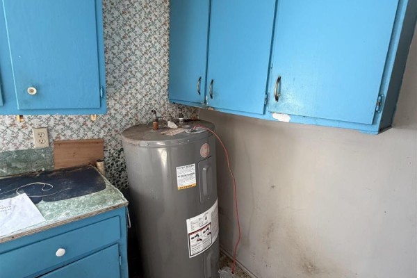 Damaged kitchen with blue cabinets, broken ceiling, and visible appliances - 119 South Street, Donkin