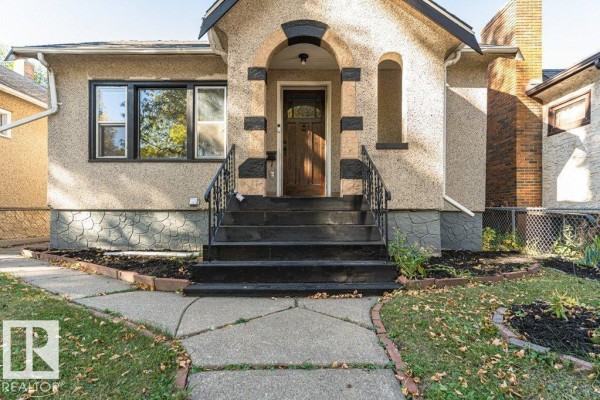 Close-up of the front entrance steps and door, with black railings and stone foundation. - 11910 94 St Nw, Edmonton