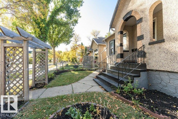 View of the front yard and wooden pergola on the left side of the house. - 11910 94 St Nw, Edmonton