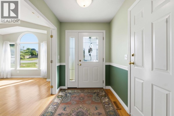 Interior view of a light green and white entryway with a patterned rug and light wood floors. - 11915 238a Street, Maple Ridge