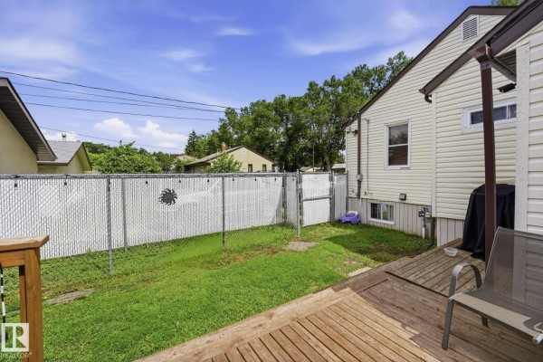 View of the backyard with a chain-link fence and a wooden deck. - 11918 47 St Nw, Edmonton