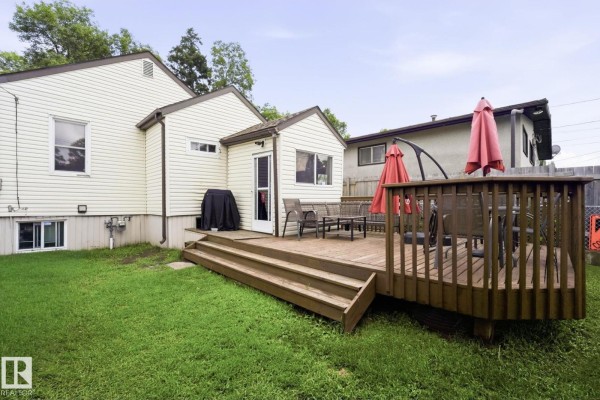 Wooden deck with patio furniture and a grill on the side of the house. - 11918 47 St Nw, Edmonton