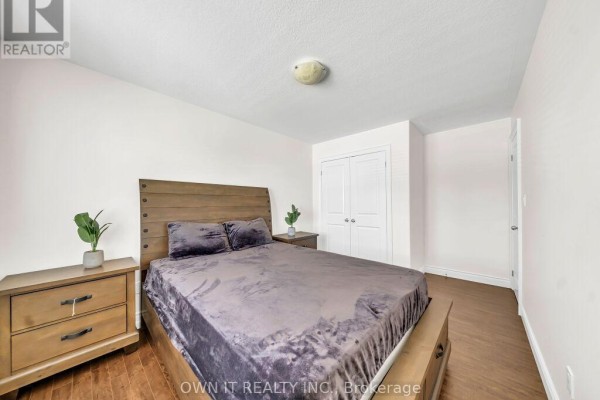 Bedroom with a wooden bed frame, two nightstands, and a closet with double doors. - 1192 Caen Avenue, Woodstock