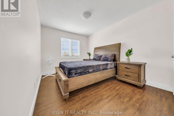 Bedroom with a wooden bed frame, two nightstands, and a window with blinds. - 1192 Caen Avenue, Woodstock