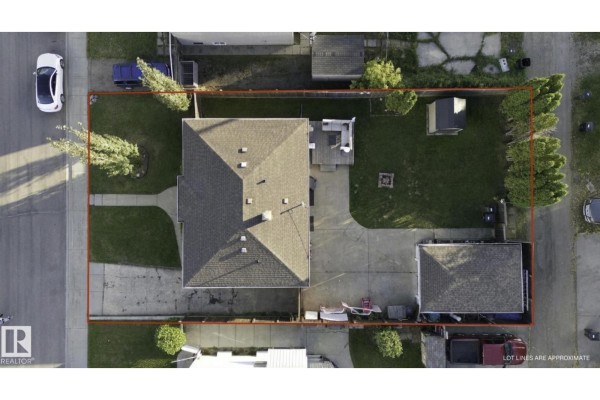 Aerial view of a rectangular property with a house, garage, backyard deck, and fenced perimeter. - 11928 127 St Nw, Edmonton