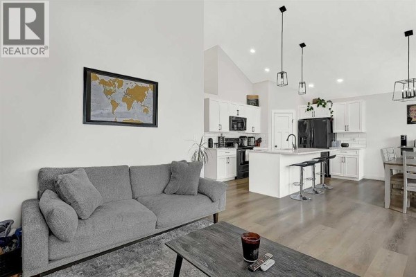Open concept living, dining, and kitchen area with a gray sofa and white cabinets. - 11929 81 Avenue, Grande Prairie
