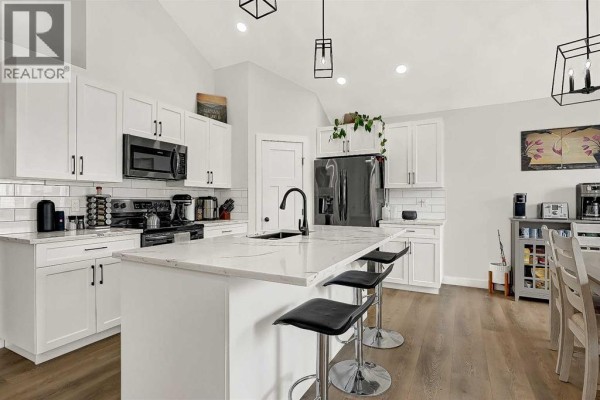White kitchen with a large island, black appliances, and pendant lighting. - 11929 81 Avenue, Grande Prairie