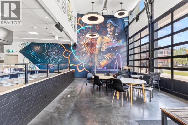 Restaurant dining area with tables and chairs, a service counter, and a large mural on the wall. - 1193 Sunset Drive, Kelowna