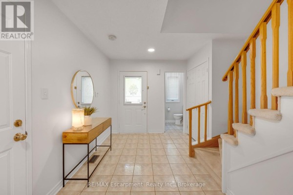 Foyer entrance with beige tile flooring, a console table, and access to a powder room. - 1194 Old Oak Drive, Oakville