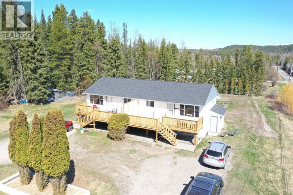 Aerial view of a white duplex house with a dark roof and surrounding trees. - 1195-1197 Omega Road, Quesnel