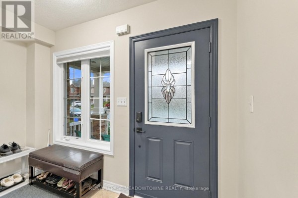 Interior view of an entryway with a dark gray door, frosted glass insert, and shoe storage bench. - 1196 Tupper Drive, Milton