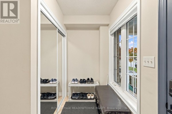 Entryway with a large mirrored closet door, shoe racks, and a bench with storage near a window. - 1196 Tupper Drive, Milton