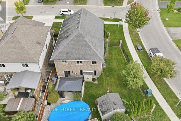 Aerial view of the backyard of a brick house showing a pool, shed, and fenced yard. - 1197 Cardinal Road, London South