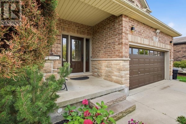 Close-up of the front entrance and garage door of a brick house with stone accents. - 1197 Cardinal Road, London South