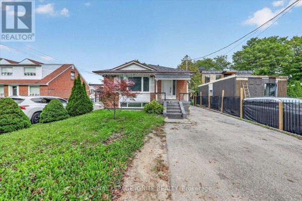 Wide shot of the front of the house and driveway with green lawn. - 1197 Pharmacy Avenue, Toronto