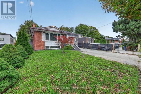 Side view of the bungalow showing the driveway and backyard fence. - 1197 Pharmacy Avenue, Toronto