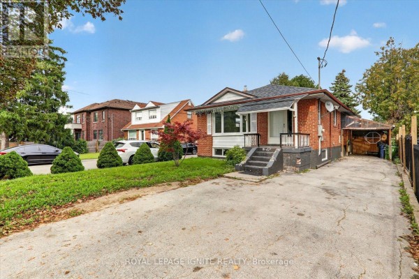 View of the house, driveway, and neighbouring buildings under a blue sky. - 1197 Pharmacy Avenue, Toronto