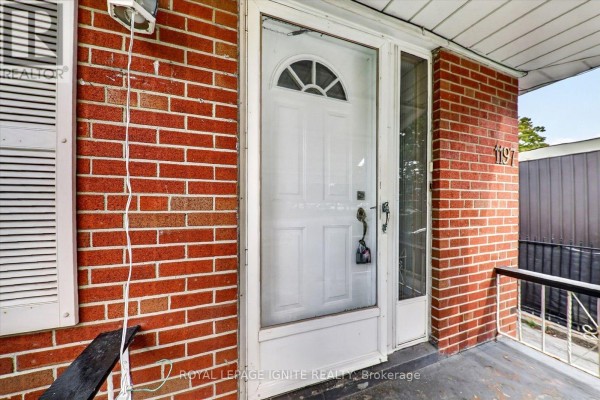 Close-up of the white front door with glass panes, surrounded by brickwork. - 1197 Pharmacy Avenue, Toronto
